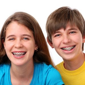 XXXL.  Young girl and boy wearing braces on white.